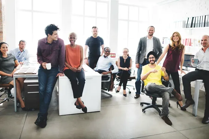 Group of diverse professionals smiling and posing together in a bright modern office workspace